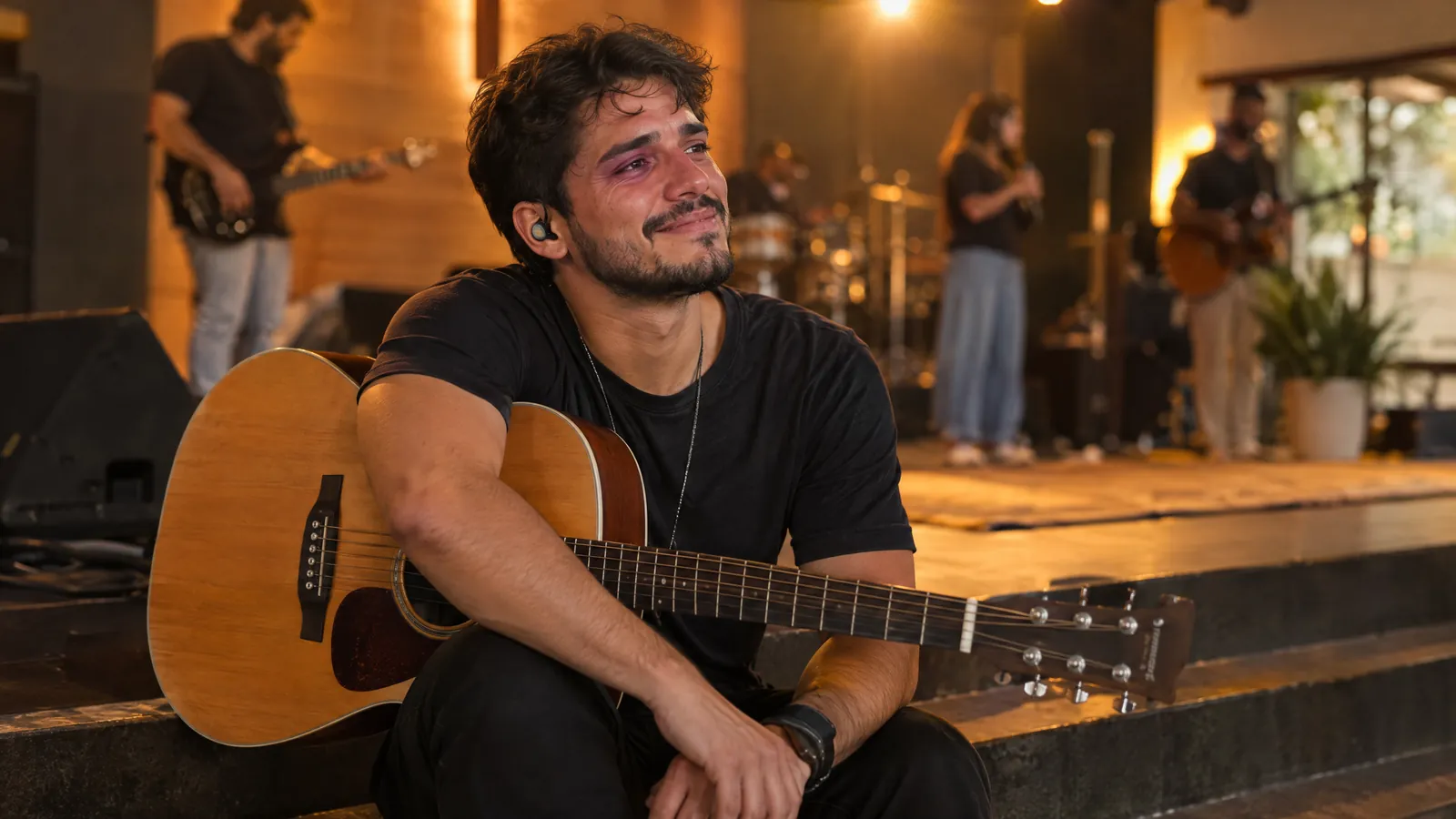 Líder de louvor com o violão no colo ouvindo emocionado a música que o ministério fez pra ele